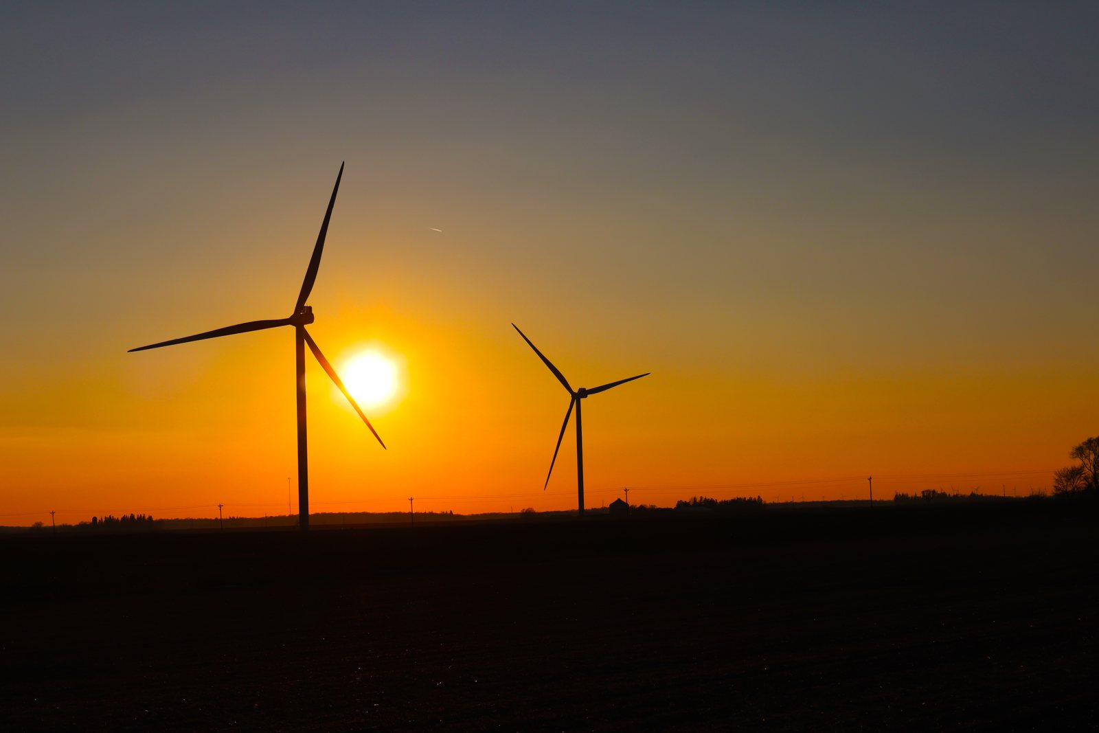 The sun setting behind wind turbines in an Iowa field